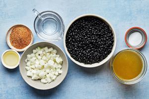 vegetable oil, diced onion, dried black beans, chicken stock, taco seasoning & salt in bowls for homemade black beans