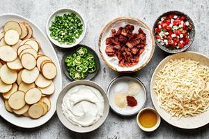 bowls of potatoes, seasonings, bacon, mozzarella, sour cream, pico de Gallo, jalapeños and green onions to make Irish nachos