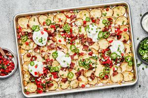 Irish nachos on a baking sheet topped with mozzarella, bacon, pico de Gallo, jalapeno, green onion and sour cream
