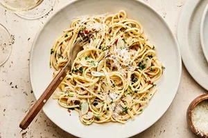 A bowl of linguine pasta tossed in a silky lemon garlic sauce, garnished with freshly grated Parmesan