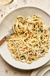 A bowl of linguine pasta tossed in a silky lemon garlic sauce, garnished with freshly grated Parmesan