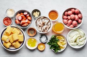 corn, shrimp, potatoes, sausage, onion, garlic, spices, parsley & lemon wedges in bowls on the counter for a low country boil