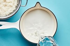 coconut milk, ginger, sugar, salt and rice in a pot to make coconut ginger rice for macadamia nut crusted fish bowls