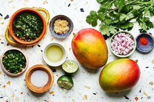 mangos, red onion, cilantro, jalapeño, lime juice, salt, brown sugar and chili powder on the counter to make mango salsa