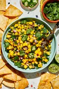 A bowl of fresh mango salsa made with diced mango, red onion, jalapeño, cilantro, and lime juice, served with chips