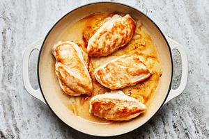chicken breasts seasoned with salt being seared in olive oil in a skillet