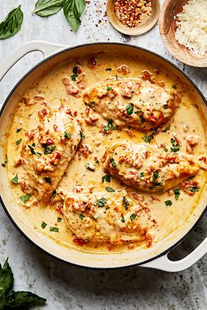 marry me chicken in a pan with a wooden spoon made with cream, chicken stock, chicken bouillon, parmesan, garlic, and spices