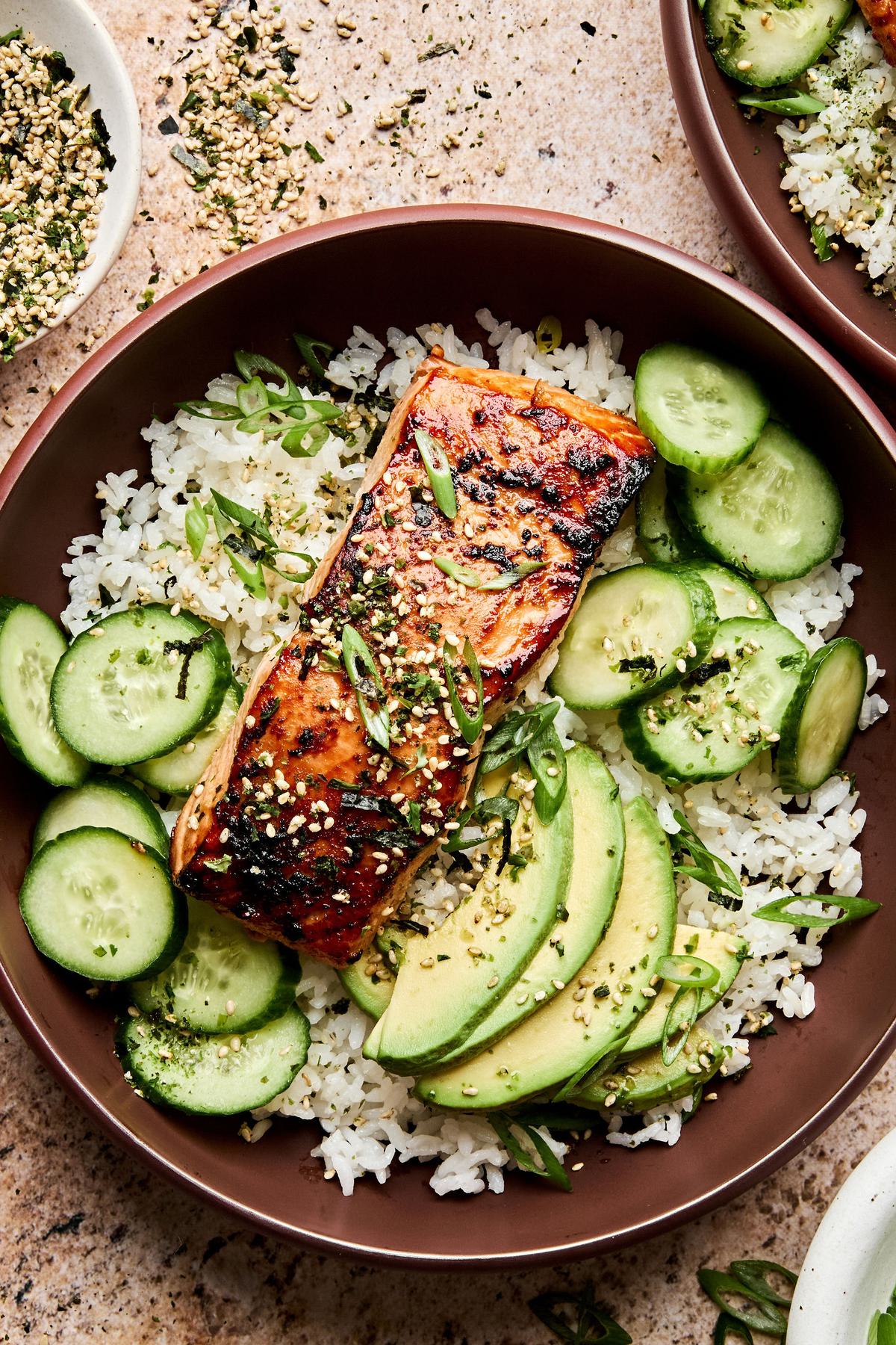 A vibrant miso salmon rice bowl with tender salmon and steamed rice topped with avocado, cucumber and furikake