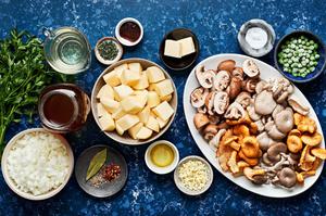 olive oil, onion, mushrooms, garlic, white wine, vegetable broth, spices, potatoes, and peas in bowls for mushroom stew