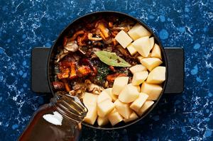mushroom stew being cooked in a pot made with mushrooms, potatoes, spices, wine and vegetable stock