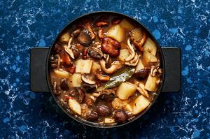 mushroom stew being cooked in a pot made with mushrooms, potatoes, spices, wine and vegetable stock