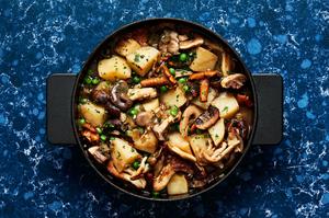 a pot of homemade mushroom stew made with mushrooms, potatoes, peas, onions, spices, vegetable stock and white wine