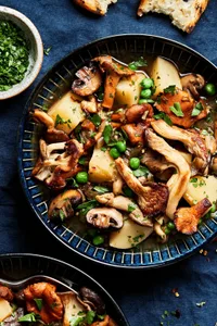 a bowl of homemade mushroom stew made with mushrooms, potatoes, peas, and onions served with crusty bread