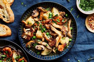 a bowl of homemade mushroom stew made with mushrooms, potatoes, peas, and onions served with crusty bread
