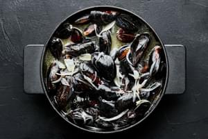 mussels being cooked in melted butter and white wine with shallots and garlic