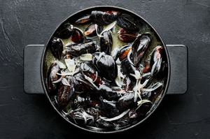 mussels being cooked in melted butter and white wine with shallots and garlic