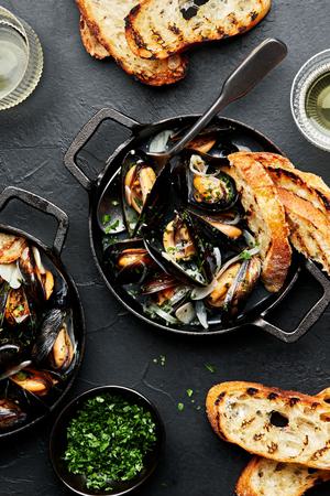 a pot of mussels in wine sauce served with crusty bread