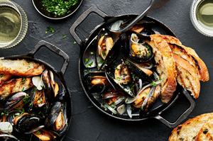 a pot of mussels in wine sauce served with crusty bread