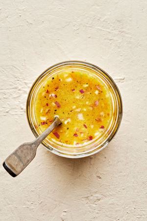 homemade orange vinaigrette in a dish with a spoon made with vinegar, olive oil orange juice, dijon, shallots, salt & pepper
