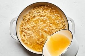 shallots, orzo, garlic, white wine and chicken broth in a pot making orzo risotto