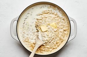 butter and heavy cream being stirred into cooked orzo to make orzo risotto