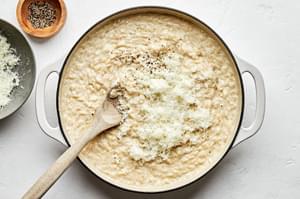 manchego cheese being added to cooked orzo with white wine and chicken broth for homemade orzo risotto