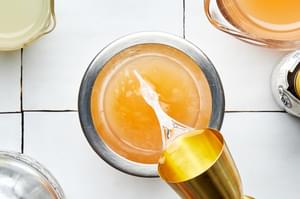tequila being poured into a cocktail shaker with grapefruit juice, lime juice and bitters for a homemade paloma