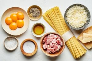 spaghetti, egg yolks, Pecorino Romano, salt, pepper, olive oil and guanciale in bowls to make homemade pasta carbonara