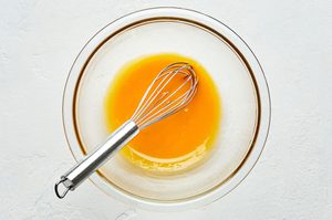 eggs yolks being beat in a glass bowl with a whisk until smooth