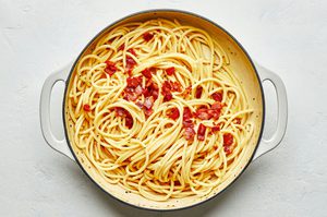pasta carbonara topped with flaky salt and Parmesan in a pot made with spaghetti, egg yolks, Pecorino Romano and guanciale