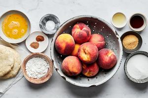 peaches, sugar, vanilla, lemon juice, spices, pie crust and a beaten egg in bowls on the counter to make homemade peach pie