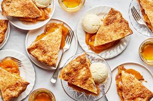 slices of homemade peach pie on plates served with scoops of vanilla ice cream