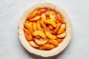 homemade pie crust in a pie pan filled with peaches