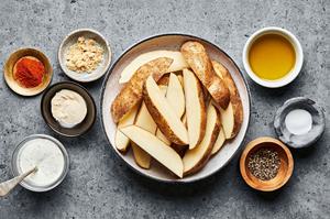 raw potato wedges, brown sugar, salt, pepper, paprika, garlic powder, olive oil and ranch in bowls to make potato wedges