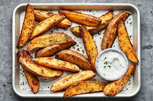 homemade potato wedges seasoned with brown sugar, salt, pepper, garlic and paprika on a baking sheet served with ranch