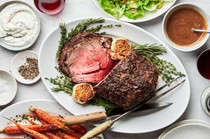 homemade prime rib sliced on a serving plate being served with roasted garlic and horseradish cream sauce