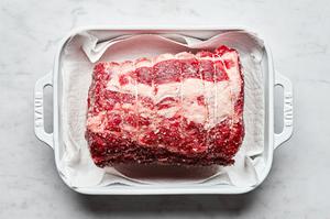 raw prime ribbed in a parchment lined baking dish seasoned all over with salt