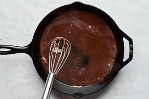 prime rib drippings, water and au jus powder being whisked together in a skillet to make a sauce for prime rib