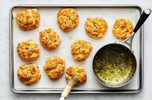 homemade red lobster cheddar bay biscuits on a baking sheet being brushed with melted butter and spices