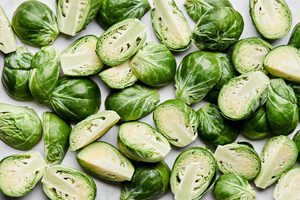 raw brussels sprouts with their ends cut off and cut in half ready to be seasoned and roasted