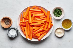 carrots, olive oil, salt, pepper, garlic powder and parsley in bowls to make roasted carrots