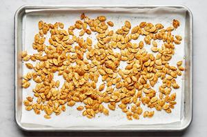 roasted pumpkins seeds on parchment seasoned with salt, garlic powder, onion powder, paprika, mustard powder and pepper