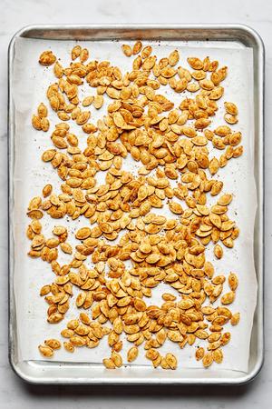 roasted pumpkins seeds on parchment seasoned with salt, garlic powder, onion powder, paprika, mustard powder and pepper