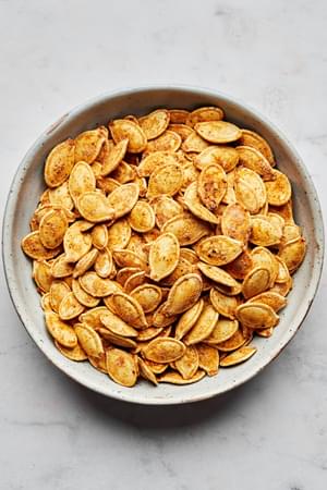 a bowl of roasted pumpkins seeds seasoned with salt, garlic powder, onion powder, paprika, mustard powder and pepper