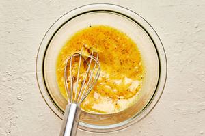 homemade orange vinaigrette being whisked in a mixing bowl made with vinegar, dijon, spices, honey, olive oil & shallot