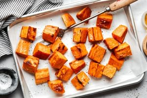 roasted sweet potatoes seasoned with olive oil, garlic powder, salt & pepper on a parchment lined baking sheet