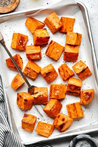 roasted sweet potatoes seasoned with olive oil, garlic powder, salt & pepper on a parchment lined baking sheet
