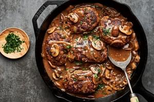 Perfectly seared Salisbury steaks in a cast iron skillet, drizzled with rich, glossy gravy and topped with parsley