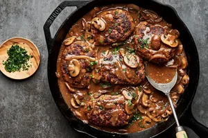 Perfectly seared Salisbury steaks in a cast iron skillet, drizzled with rich, glossy gravy and topped with parsley