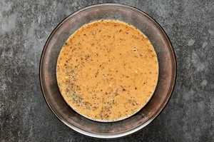 Milk being poured into a bowl with eggs, ketchup, spices, and seasonings, ready to mix for Salisbury steak patties.